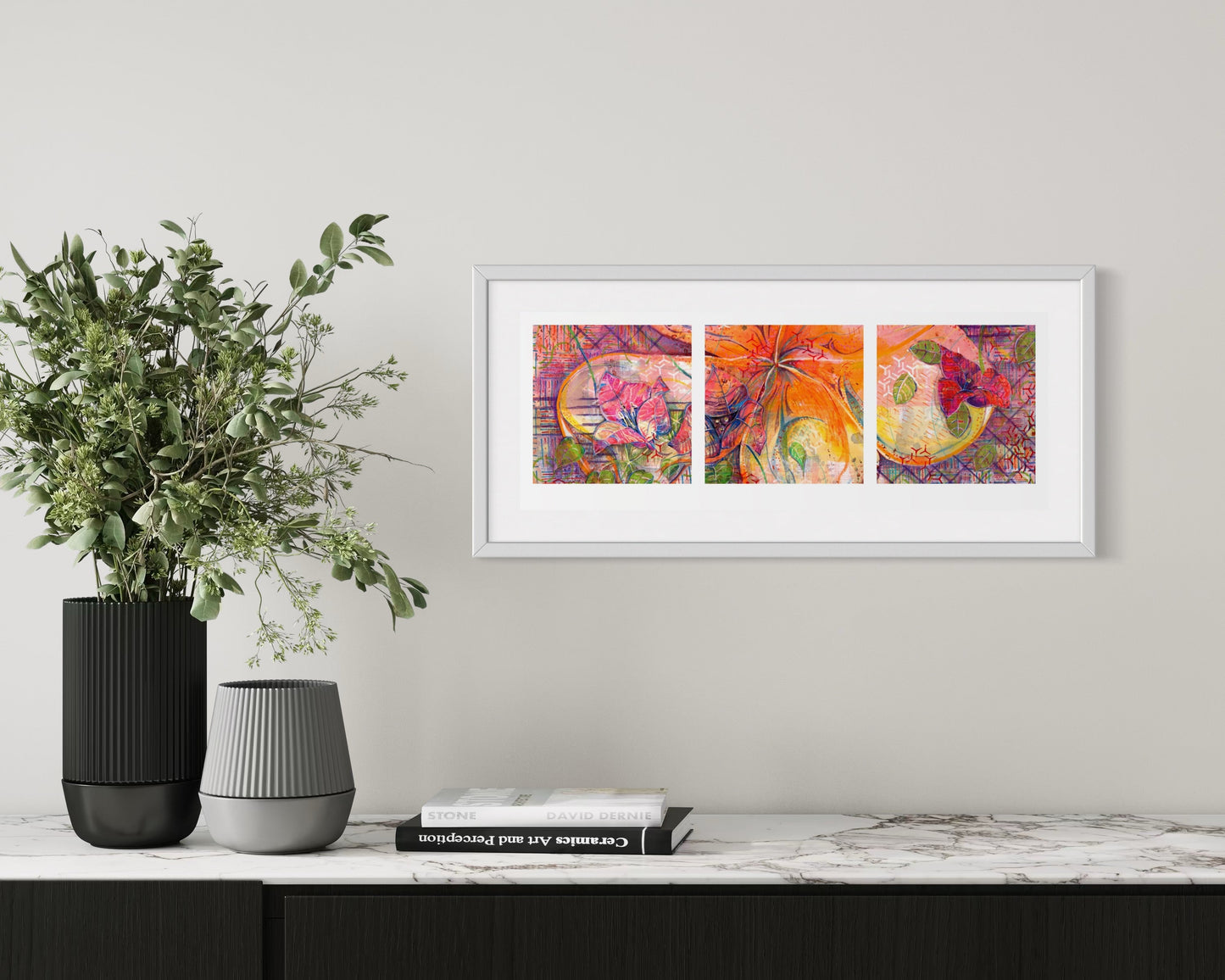 Framed abstract art triptych on a wall above a console table with decorative items.